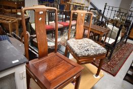 A matched pair of Oriental hardwood dining chairs in the Chinese style having solid seats
