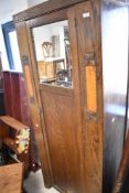 An early 20th Century oak wardrobe or hall robe of narrow proportions with part mirror door,