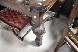An early 20th Century oak drawer leaf dining table on carved column supports with shaped stretcher