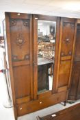 An early 20th Century oak mirror door wardrobe having long drawer base (missing top plinth), width