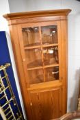 A vintage pine corner display cabinet with cupboard to base