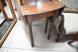 An early 20th century barley twist oak gate legged table, of traditional design with oval flaps, and
