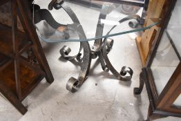 A retro style wrought iron and glass top coffee table having scroll legs and shaped top, approx.
