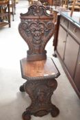 An interesting 19th Century mahogany hall chair having extensive carving including 'Green Man' to