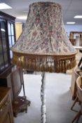 A traditional painted standard lamp having barley twist column and floral tassled shade