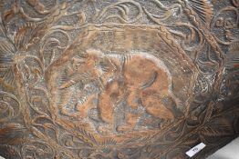 A tribal art style carved occasional table with elephant decoration and folding frame