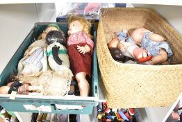 A collection of vintage dolls and toys presented in a green plastic crate and a wicker basket. The