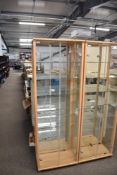 A pair of contemporary upright display cabinets, constructed with a light-toned wood frame, possibly