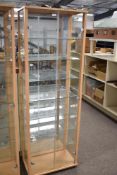 A pair of tall, upright display cabinets featuring light wood-effect frames. Each unit is