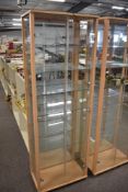 A pair of matching tall, upright display cabinets featuring light wood-effect frames in a beech
