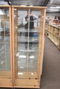 A pair of modern freestanding display cabinets featuring a light wood-effect finish resembling