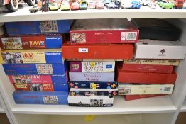 A collection of various boxed jigsaw puzzles, primarily 1000 and 500-piece examples, featuring a