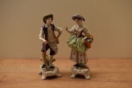 A pair of German porcelain figures depicted as a gentleman resting on a spade and a female holding a