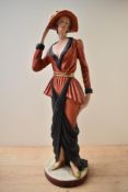 A large Art Deco style pottery figurine depicting a female in a long red and black dress wearing a