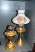 Two early 20th-century brass oil lamps, to feature a milk glass shade having a decorative duck