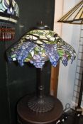 A contemporary Tiffany-style table lamp, featuring a blue and lavendar Wisteria motif shade with a