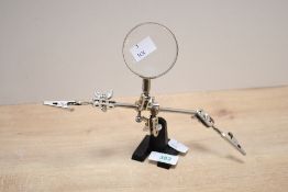 A vintage metal helping hands soldering stand with magnifying glass, featuring two adjustable
