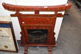 A large 20th-century Japanese-style red lacquered fire screen, of traditional gate form with