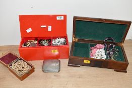 A wooden jewellery box along with a red plastic jewellery box, both containing an assortment of