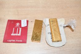 A Dunhill lighter with replacement lighter flints, along with a Cartier lighter
