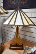 A contemporary Tiffany-style table lamp, featuring a panelled Art Deco-style shade with a scrolled