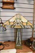 A contemporary Tiffany-style table lamp, having a stepped pyramid shade and rectangular base