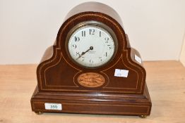 An Edwardian inlaid mahogany mantle clock, featuring a French 8-day movement and an enamelled convex