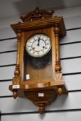 A 20th-century German oak Hermle wall regulator clock, featuring an ornate graduated pediment upon