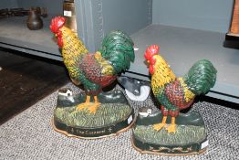 Two vintage cast iron Cockerel door stops, featuring colourful plumage upon field-like bases,