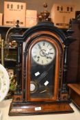A late 19th-century ebonised walnut mantel clock, featuring an arched top with finial and a turned