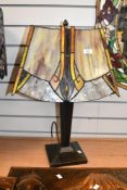 A contemporary Tiffany-style table lamp, having an Art Deco-style geometric shade of ornages and