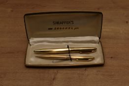 A boxed Sheaffer Touchdown Triumph Snorkel fill fountain pen and pencil set in parallel lined gold