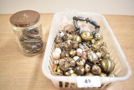 A small basket containing a selection of vintage metal sleigh bells, vintage glass beads and a jar