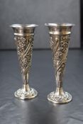 A pair of late Victorian silver vases, of fluted form having embossed floral and scroll