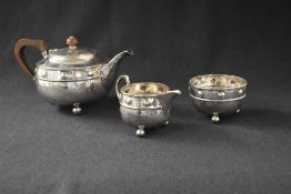 A George V silver Arts & Crafts silver three-piece tea set, comprising a teapot, sugar and cream, of