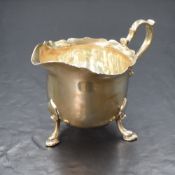 A George V silver cream jug, having a Chippendale style rim with generous spout opposed by a