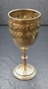 A Victorian silver cup, having embossed foliate decoration raised on a knopped stem with a