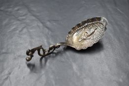 A Victorian Dutch import silver 'monkey spoon' having a decorative scroll handle and embossed bowl