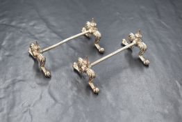 A cased pair of Victorian silver knife rests, the finial tops over paw style legs, marks for