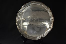 A George V silver salver, of circular form having a lobed rim with a central cartouche having ribbon