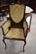 An Edwardian mahogany carver salon chair having later upholstery to shield back, arm supports and