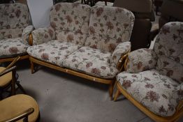 An Ercol three piece cottage suite comprising settee and two chairs with foliate upholstery , in