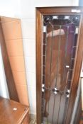 A vintage oak narrow display cabinet having leaded glass door and later peach glass mirror back