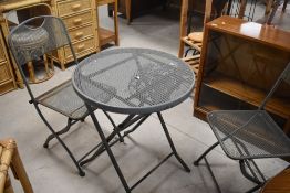 A modern metal folding table and two similar chairs, table diameter approx. 60cm, surface rust
