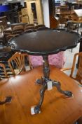 An early 20th Century mahogany occasional table having scallop top on turned column and triple splay