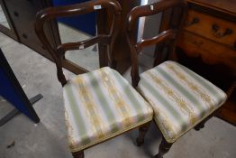 A pair of Victorian mahogany railback dining chairs having overstuffed seats with later upholstery
