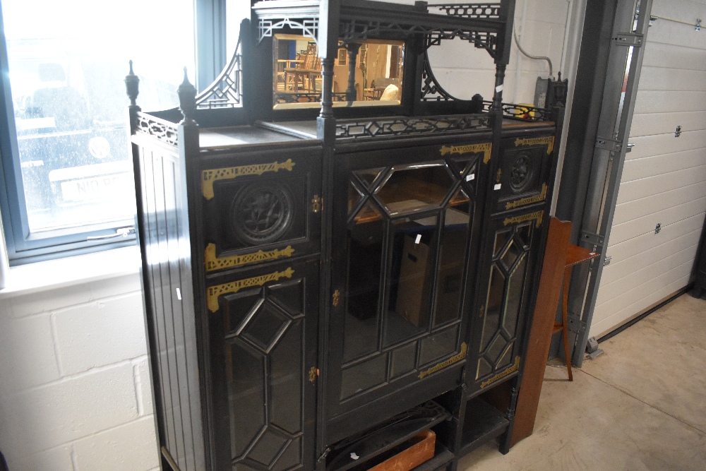 A late Victorian ebonised display cabinet in the Aesthetic style, having elaborate brass hinges,