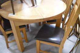 A modern golden oak extending dining table of circular form, diameter approx. 120cm, plus