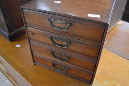 A golden oak miniature/specimen chest of four drawers with internal label for Henry Stone & Son,