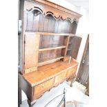 A Georgian oak dresser having plate rack with two cupboards and trinket drawers over open base